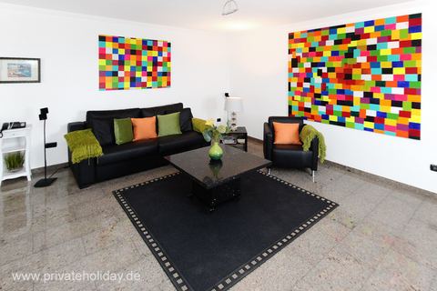 Salon z czarną sofą i kolorowymi obrazami – Alcalá, Tenerife