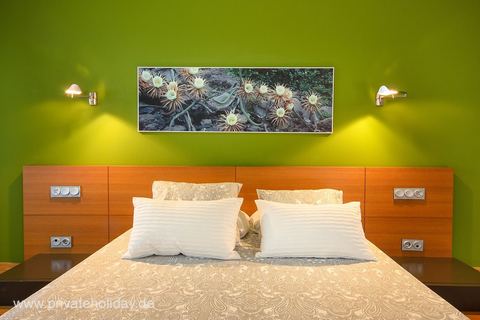 Tweepersoonsbed tegen groene accentmuur – Playa Blanca, Lanzarote