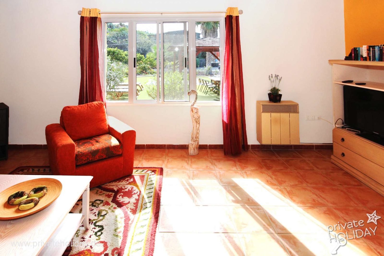 Lichte woonkamer met rode fauteuil en tuindeur – Chio, Teneriffa