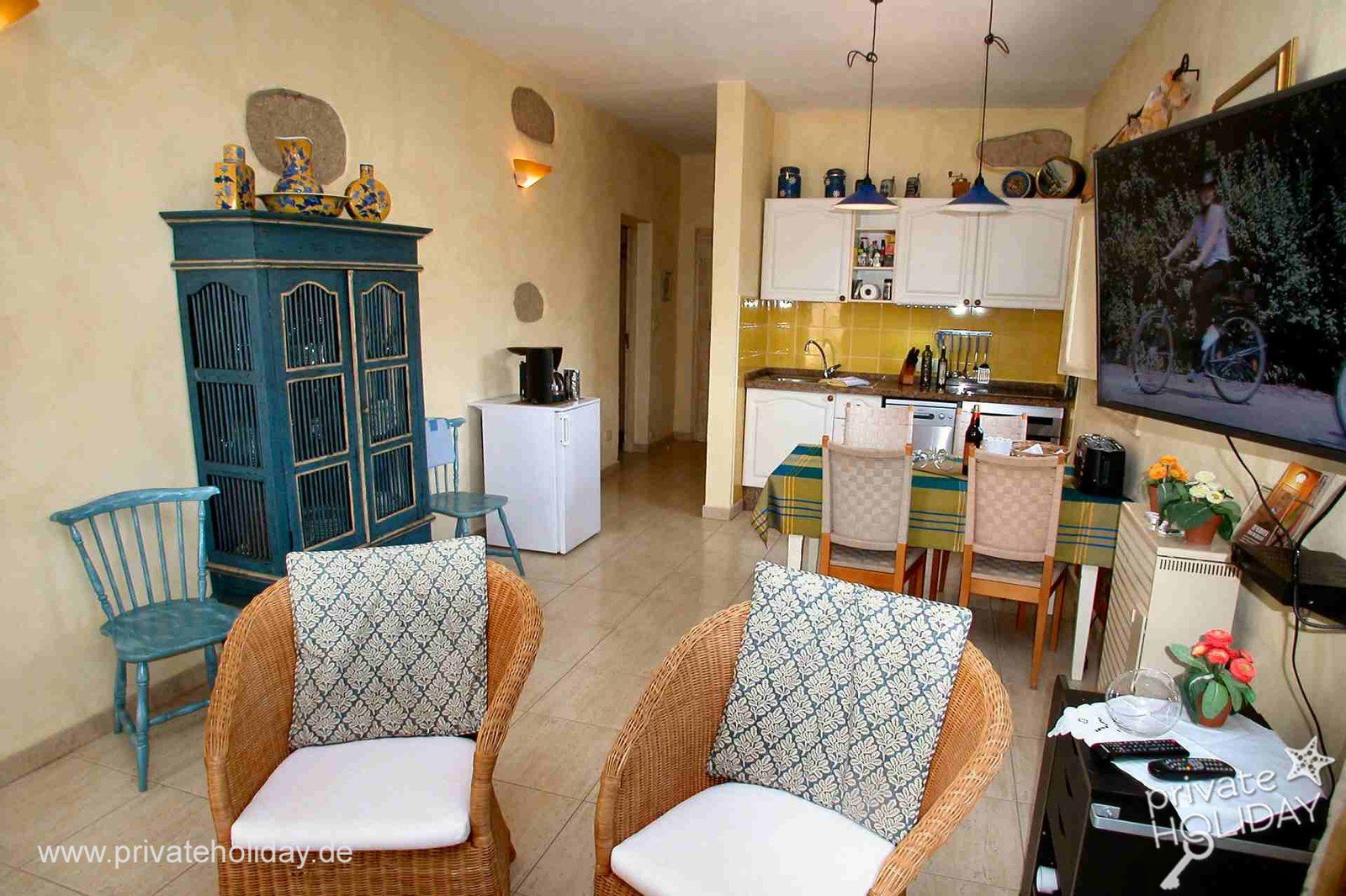 Cocina-comedor con sillas de ratán y televisor plano – Guía de Isora, Tenerife